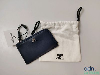un portefeuille noir et blanc et un sac blanc posés sur une table