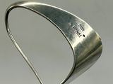 a metal sculpture of a curved object on a white surface