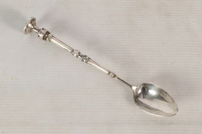 a silver spoon with a handle on a white surface