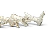two silver figurines of animals on a white surface