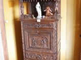 une armoire en bois surmontée d'une statue, dans une pièce