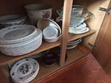 many plates and bowls stacked on a shelf in a cabinet