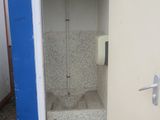 a toilet in the corner of a building with a blue door