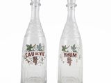 two clear glass bottles with red and green designs on them