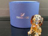 une figurine de chien en verre posée sur une table, à côté d'une boîte bleue