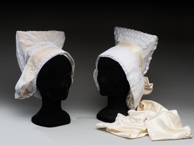 deux têtes de mannequin coiffées de chapeaux, exposées sur une surface grise
