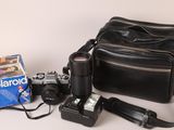 a camera, a bag, and a polaroid camera on a table