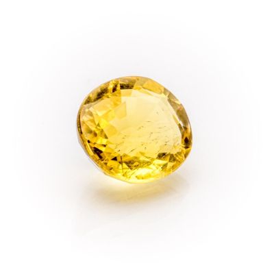 a close up of a yellow sapphire stone on a white surface
