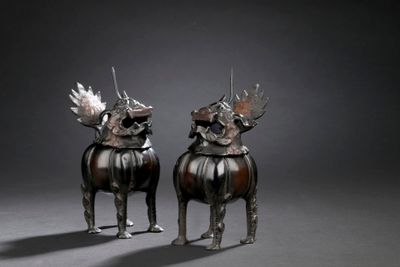 pair of bronze sculptures of two dogs with horns on their heads