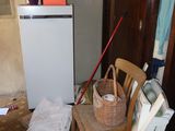 a small refrigerator and a chair in the corner of a room