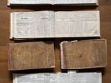 Plusieurs vieux livres sont empilés les uns sur les autres sur un plancher en bois.