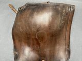 a hand pointing at a brown leather purse on a table