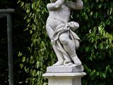 a statue of a boy holding a tennis racket in a garden