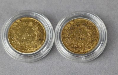 two pieces of gold coins, one of which is in a glass case