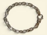 a silver bracelet with a clasp on a white surface