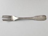 une fourchette en argent posée sur une surface blanche, avec une fourchette au milieu de la fourchette