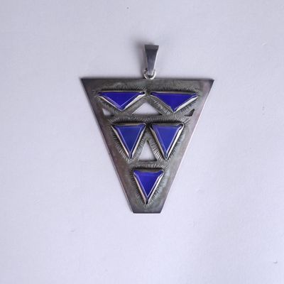 a silver and blue triangle shaped pendant on a white surface