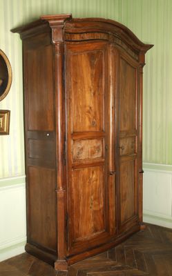 une grande armoire en bois dans une pièce où est accrochée une horloge au mur