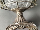 an antique silver plate with a glass vase on a stand