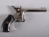 un vieux revolver argenté avec une crosse noire sur un fond blanc