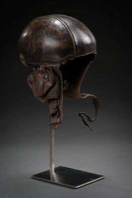 an old helmet on a metal stand with a black background