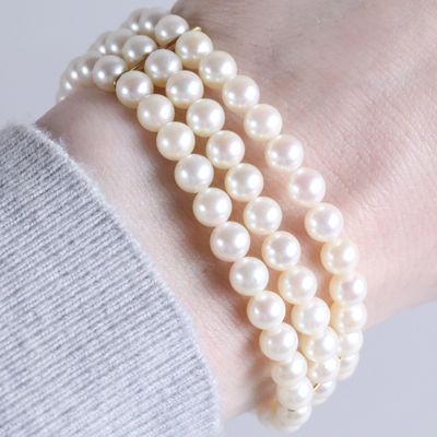 a close up of a person wearing a bracelet with pearls on it