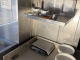 a small kitchen with a stove, sink, and shelves