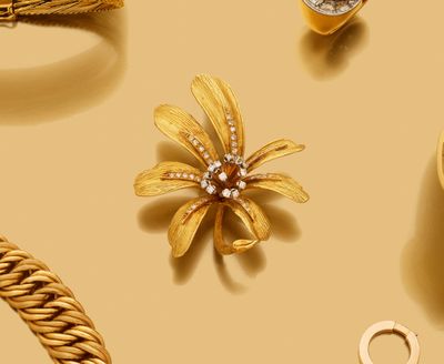 des bijoux en or sur fond beige, avec une broche en forme de fleur en or et une chaîne en or