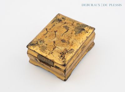 une boîte dorée ornée d'une image, posée sur une surface blanche