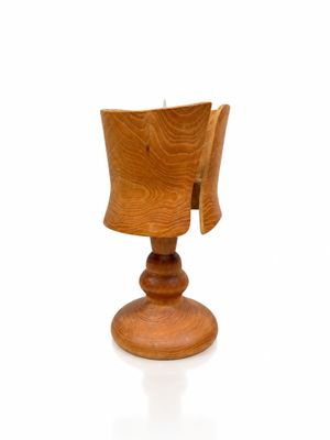 une petite tasse en bois posée sur un socle, sur une surface blanche