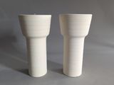 two white vases sitting next to each other on a table