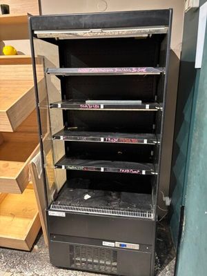 a black refrigerator that is next to a set of stairs