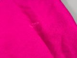 un tissu rose avec un trou au milieu, posé sur une surface blanche