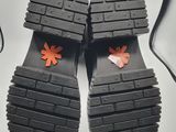 pair of black sandals with orange flowers on them sitting on a white surface