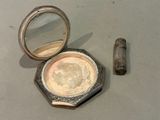 a small mirror and a small metal container on a table