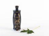 a small black vase with a gold leaf on it