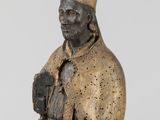 an old statue of a man with a hat and robe holding a book