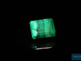a close up of a green emerald stone on a black surface