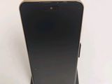 un gros plan d'un téléphone noir posé sur un socle, sur une surface blanche