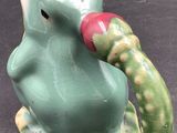 a figurine of a green elephant with a red ball in its mouth