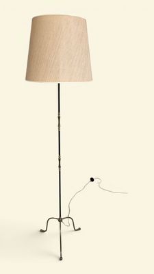 la lampe repose sur un pied en métal et est dotée d'un abat-jour beige