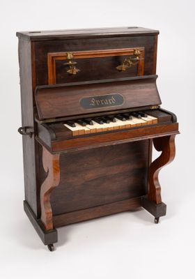 Un vieux piano est posé sur un support sur lequel est accrochée une pancarte