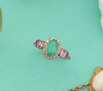 deux bagues et un collier posés sur un fond vert parsemé de coquillages