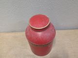 a red vase sitting on a table with a white wall in the background