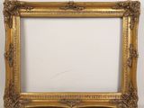 a gold picture frame with ornate carvings and a white background