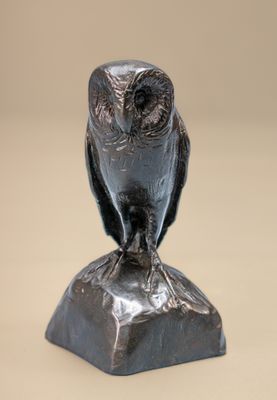 statue of an owl sitting on a rock on a beige background