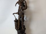 bronze statue of a woman holding a basket and a bird on a pedestal
