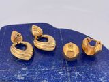 un gros plan sur trois paires de boucles d'oreilles en or posées sur une pierre bleue