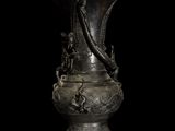 a silver vase with a dragon on it on a black background