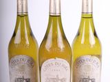 trois bouteilles de vin blanc posées l'une à côté de l'autre sur une surface blanche